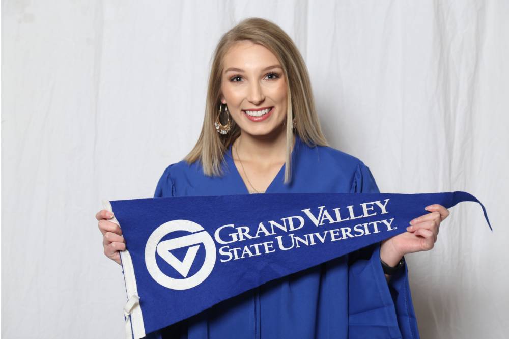 An upcoming graduate poses with GV flag at GradFest
